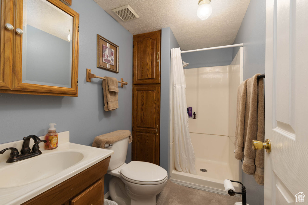 Full bathroom with a shower stall, toilet, vanity, and a textured ceiling