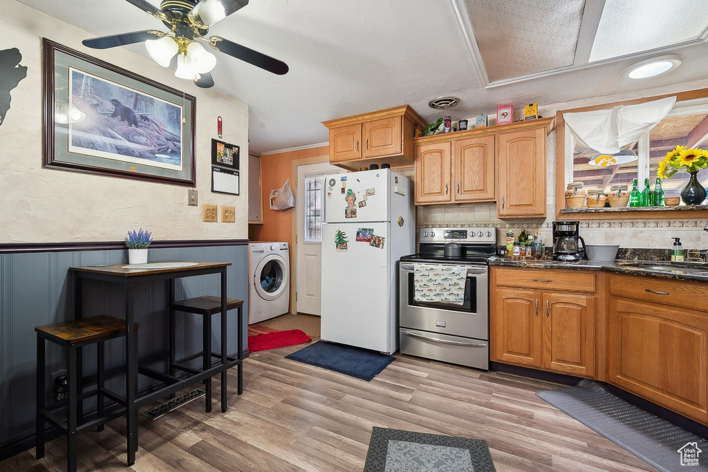 Kitchen featuring washer / dryer, freestanding refrigerator, stainless steel electric range, a ceiling fan, and wainscoting
