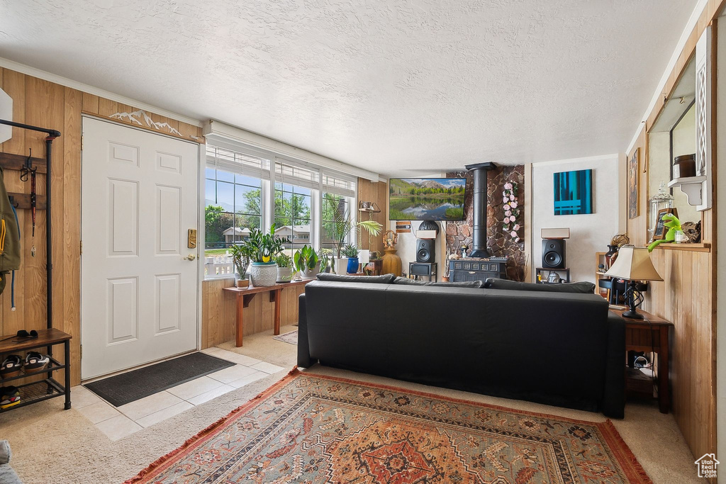 Entrance foyer featuring a wood stove, wooden walls, a textured ceiling, and light tile patterned floors
