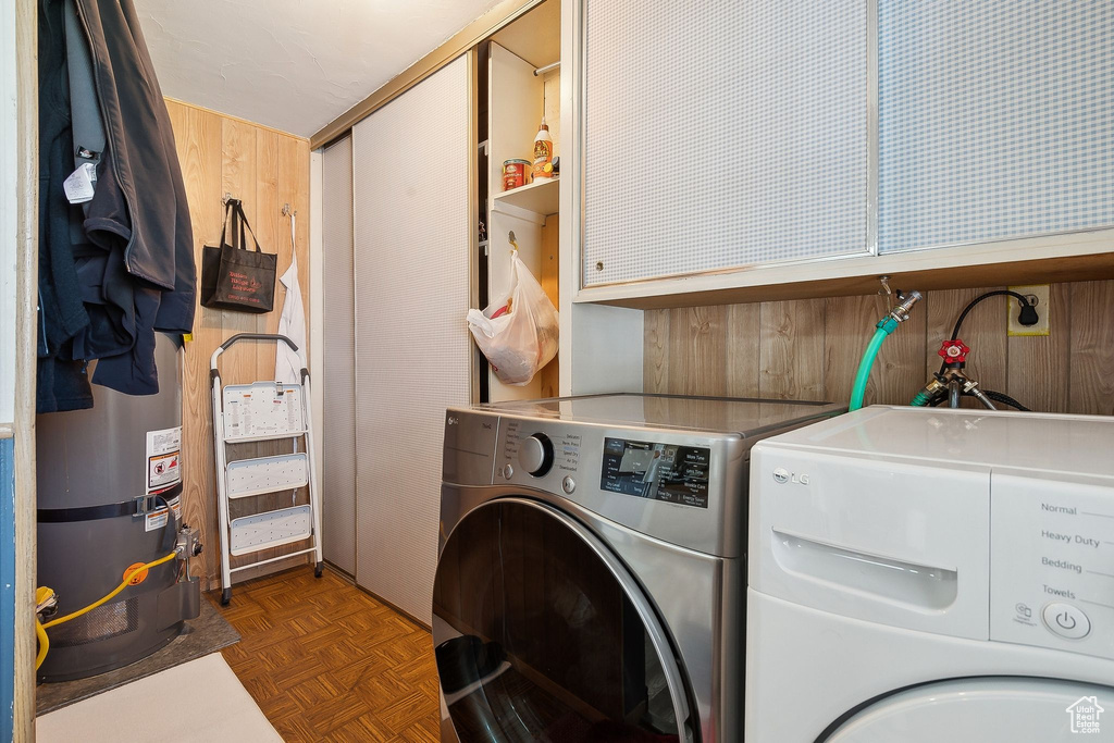 Washroom featuring cabinet space, washing machine and dryer, and wooden walls