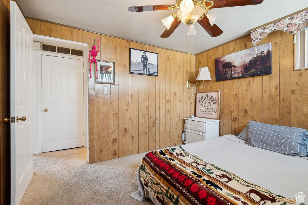 Bedroom with carpet, wood walls, and ceiling fan