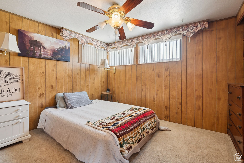 Bedroom with carpet, wood walls, and ceiling fan