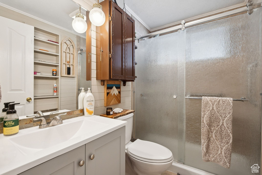 Bathroom with a shower stall, toilet, vanity, and crown molding