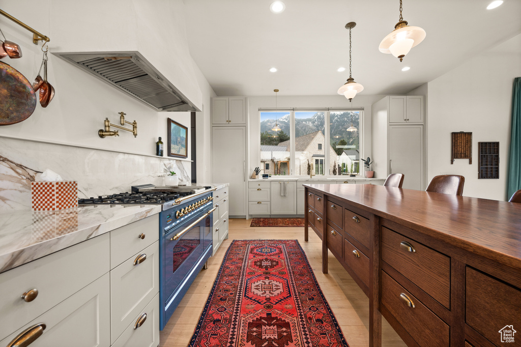 Kitchen featuring double oven range, exhaust hood, tasteful backsplash, recessed lighting, and hanging light fixtures
