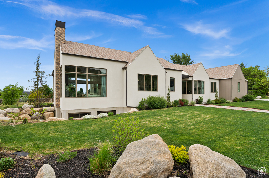 View of front of house with a chimney, stucco siding, and a front lawn