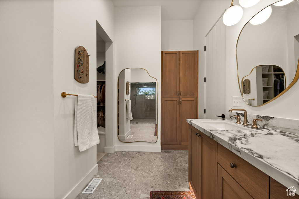 Bathroom with vanity, baseboards, and a spacious closet
