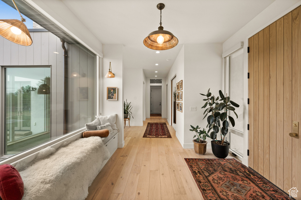 Corridor with light wood-type flooring, baseboards, recessed lighting, and wood walls