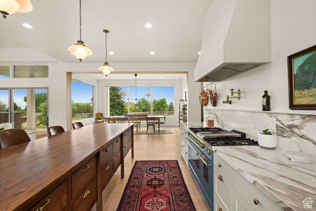 Kitchen featuring stainless steel stove, custom exhaust hood, recessed lighting, backsplash, and butcher block counters