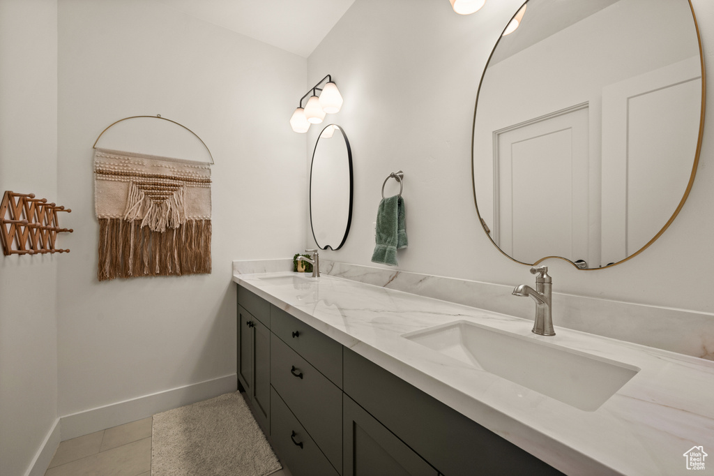Bathroom with double vanity, baseboards, and tile patterned floors