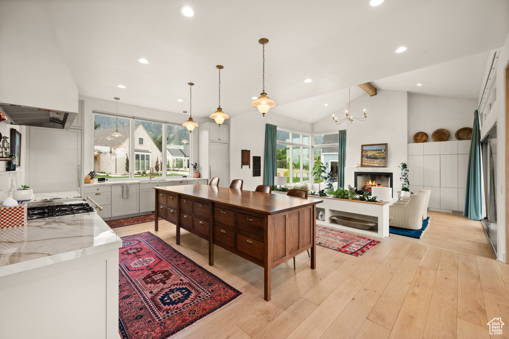 Kitchen with custom range hood, healthy amount of natural light, light wood-style floors, decorative light fixtures, and recessed lighting