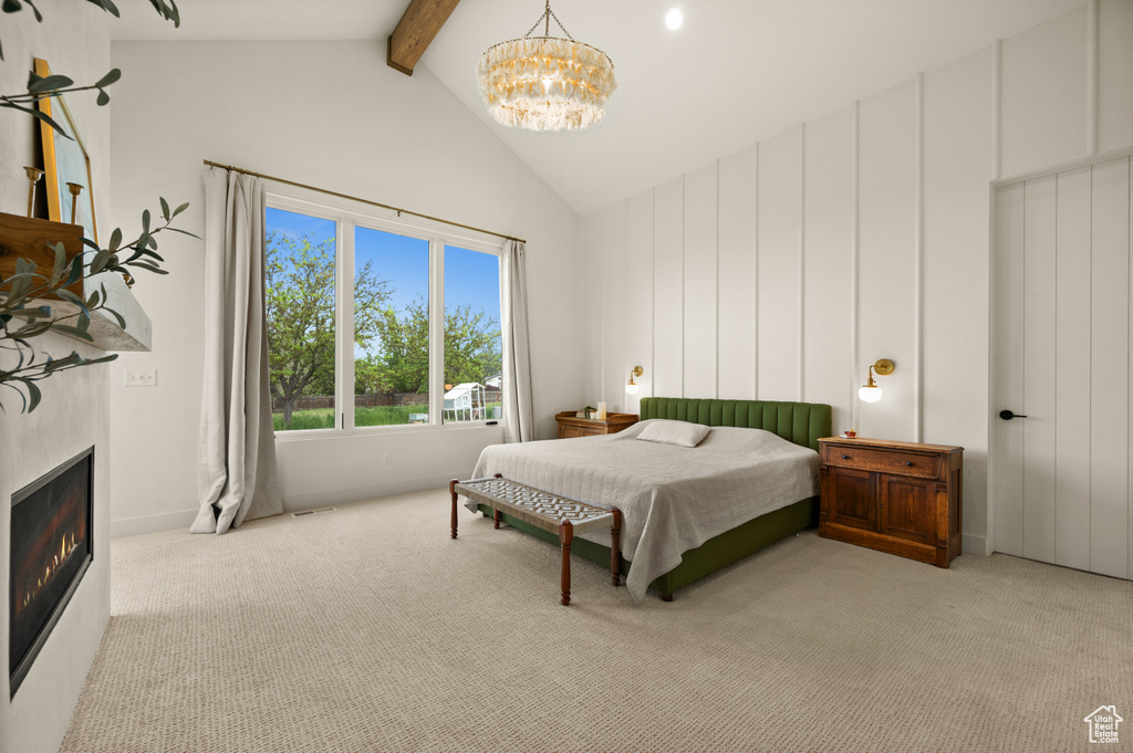 Bedroom featuring beam ceiling, carpet flooring, a chandelier, high vaulted ceiling, and a glass covered fireplace