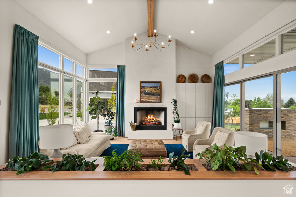 Living room featuring beamed ceiling, high vaulted ceiling, a warm lit fireplace, a chandelier, and recessed lighting