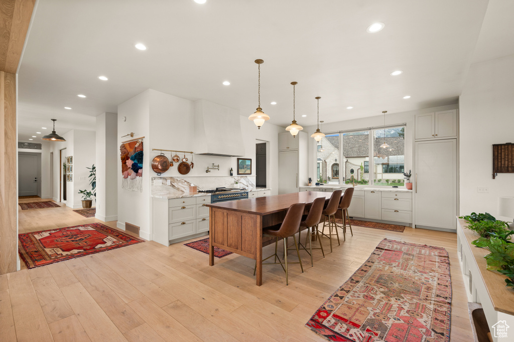 Kitchen with range hood, recessed lighting, light wood finished floors, and pendant lighting