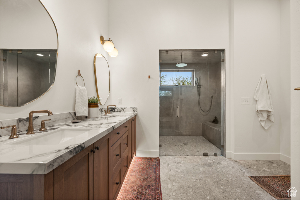 Bathroom with baseboards, a shower stall, and double vanity