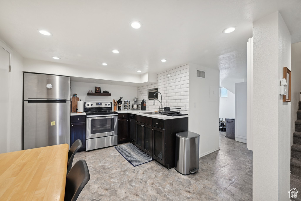 Kitchen featuring stainless steel appliances, recessed lighting, a sink, light countertops, and decorative backsplash
