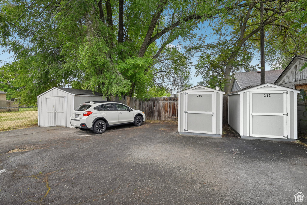 View of vehicle parking featuring a shed and fence