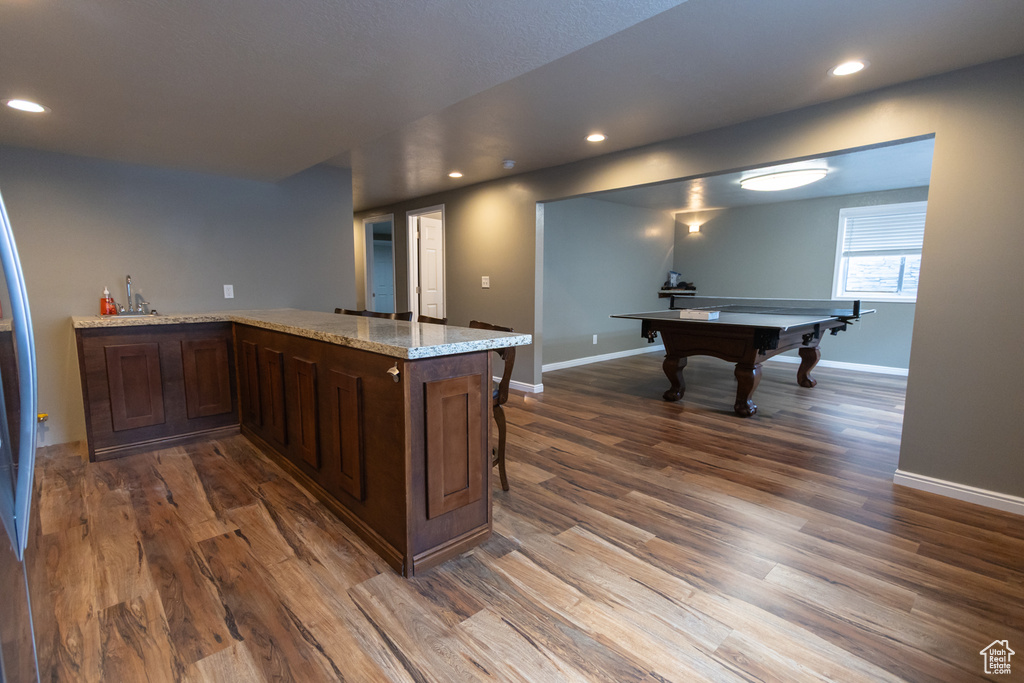 Kitchen featuring dark wood finished floors, recessed lighting, baseboards, pool table, and dark brown cabinets