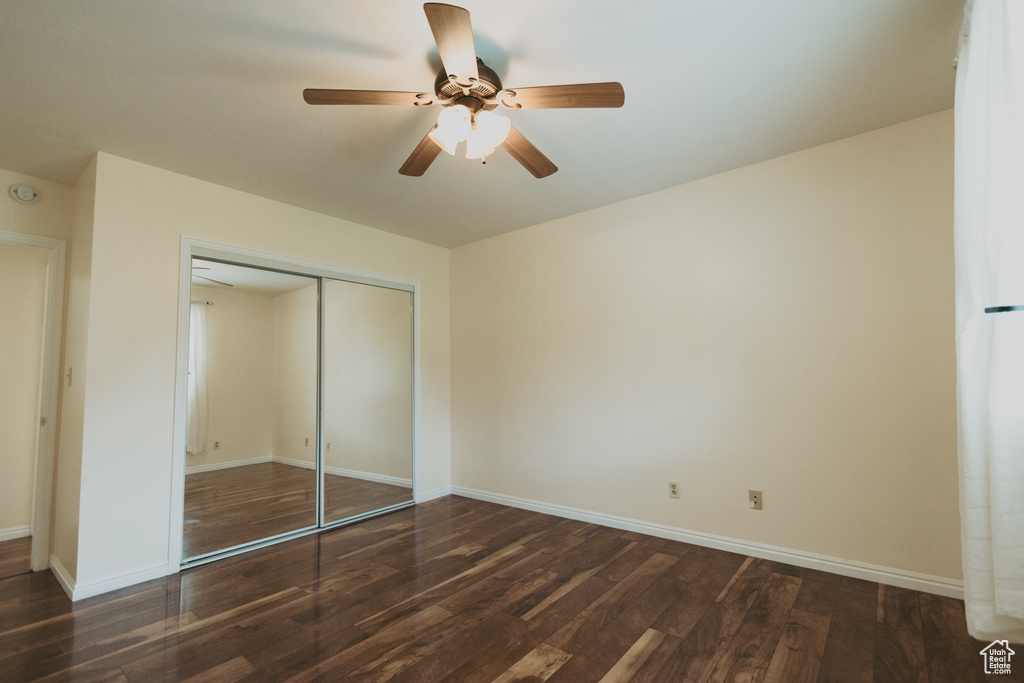 Unfurnished bedroom with wood finished floors, a closet, baseboards, and ceiling fan