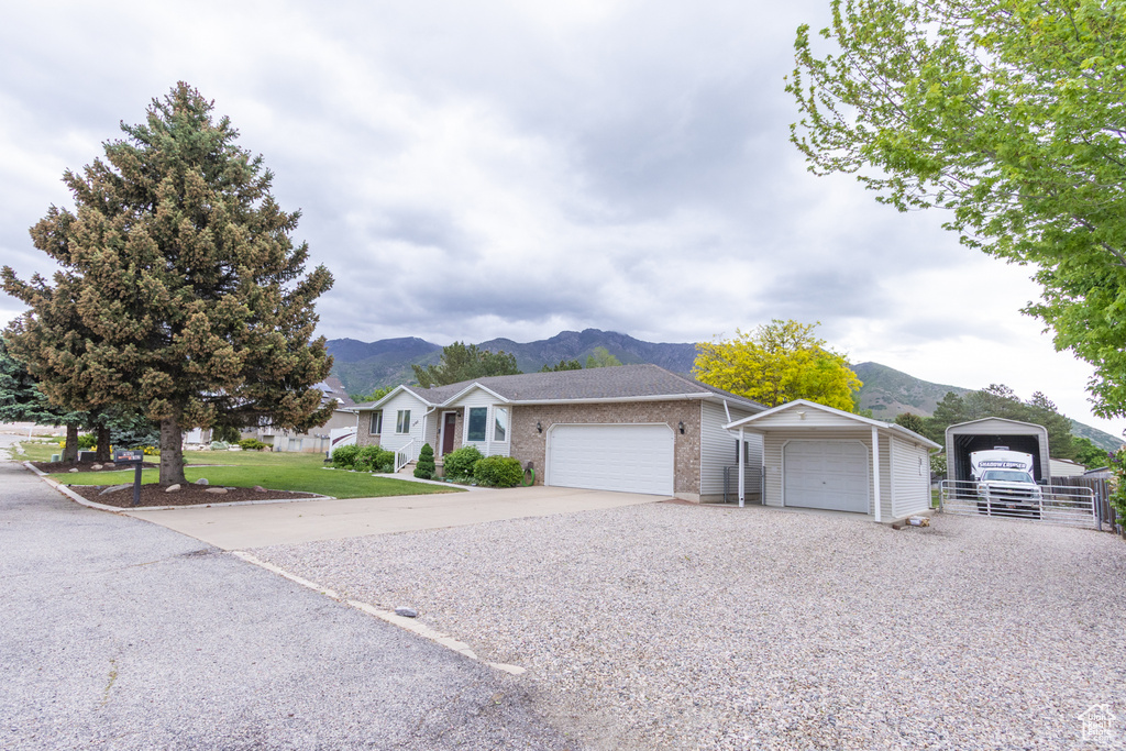 Ranch-style home featuring a mountain view, gravel driveway, brick siding, and a garage