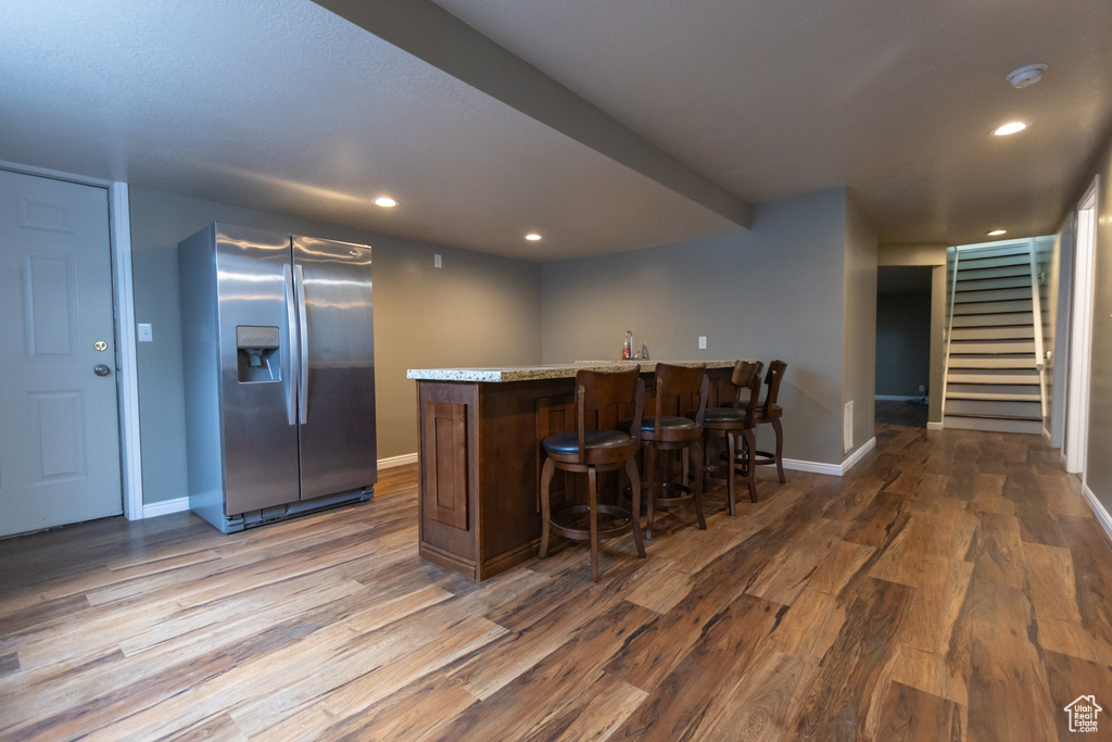 Kitchen featuring stainless steel fridge, wood finished floors, baseboards, a peninsula, and recessed lighting