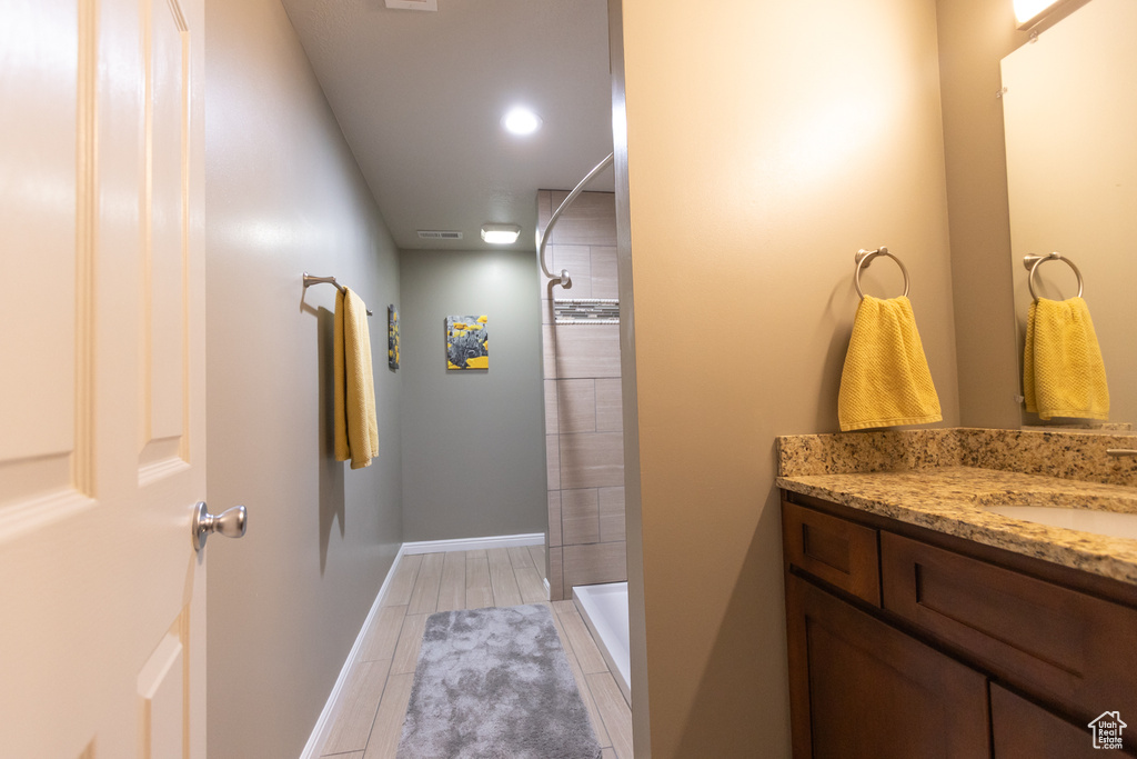 Full bath featuring a tile shower, vanity, tile patterned flooring, and baseboards