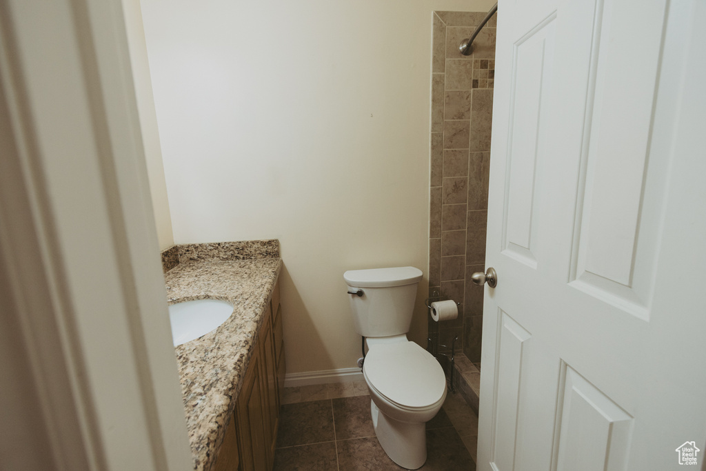 Full bathroom with vanity, toilet, tile patterned floors, a tile shower, and baseboards