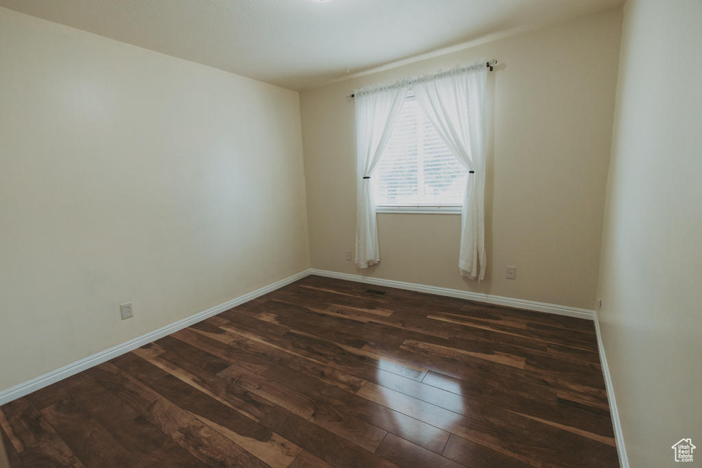 Empty room featuring dark wood-style flooring and baseboards