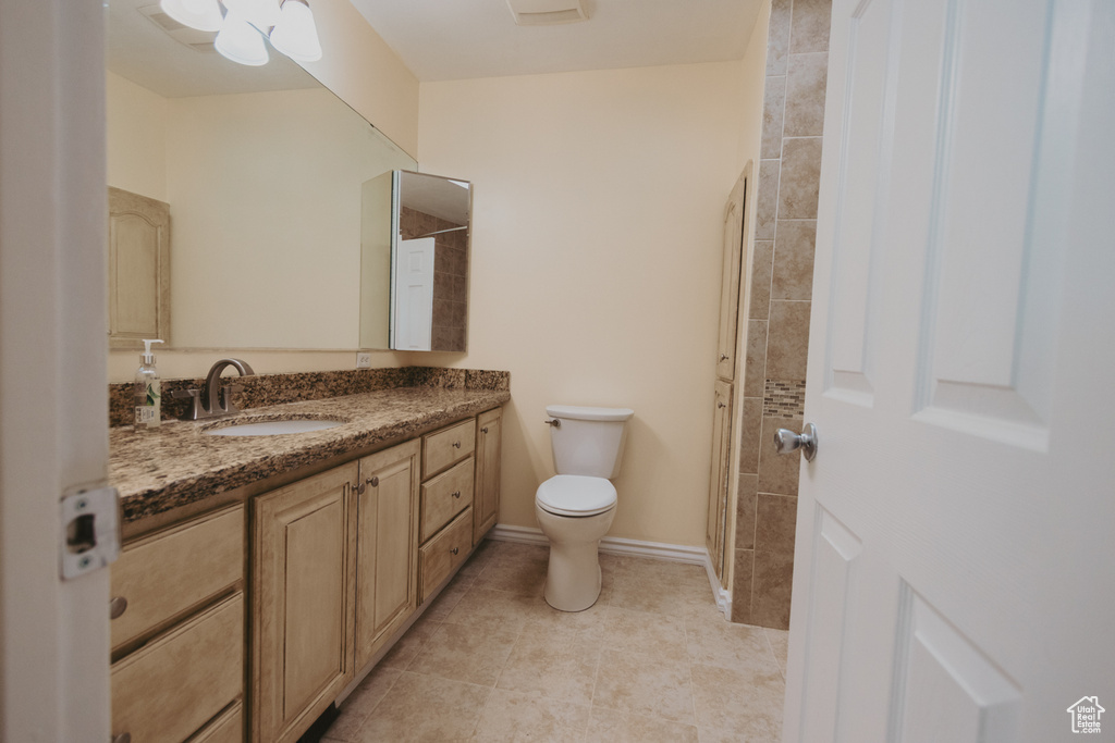 Full bath with toilet, vanity, tile patterned floors, and baseboards