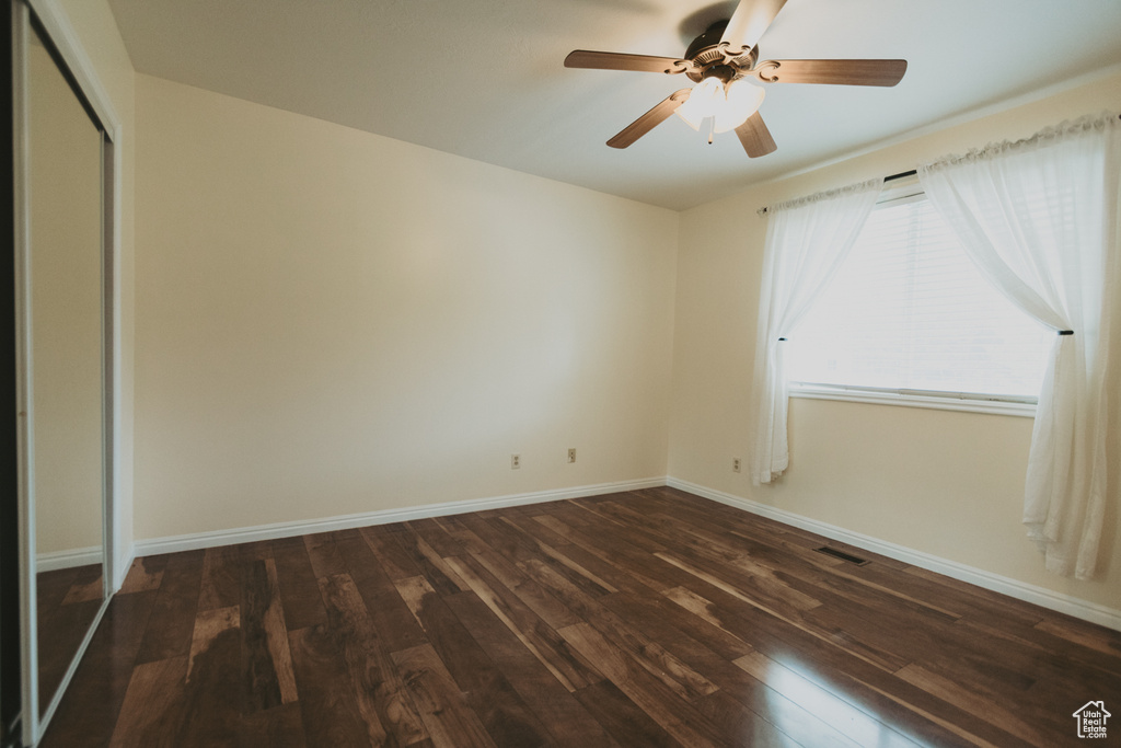 Unfurnished bedroom with dark wood-type flooring, baseboards, a closet, and ceiling fan