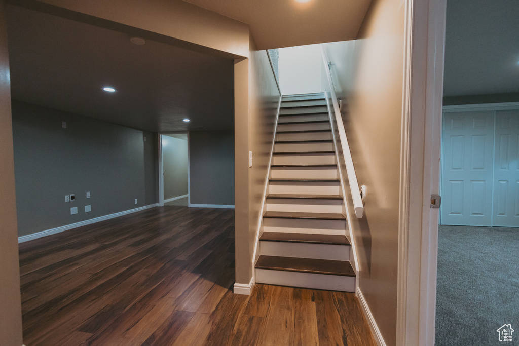Staircase with wood finished floors, baseboards, and recessed lighting
