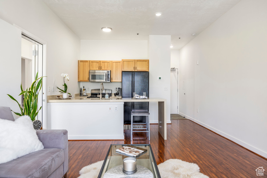 Kitchen with stainless steel microwave, dark wood-style flooring, a peninsula, light countertops, and recessed lighting