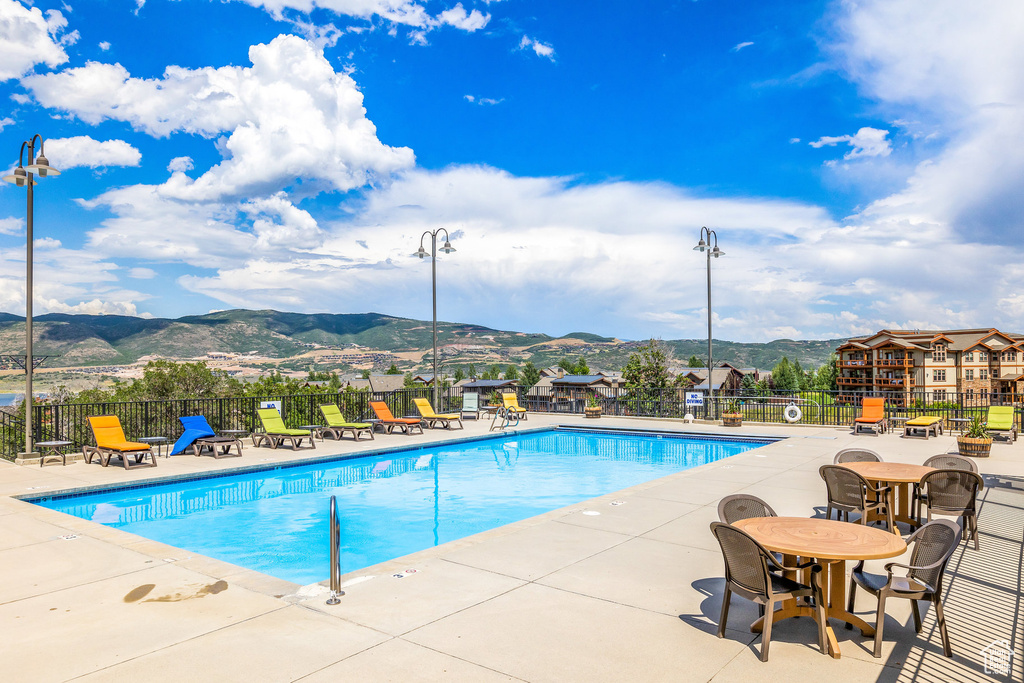 Community pool with a mountain view, fence, and a patio