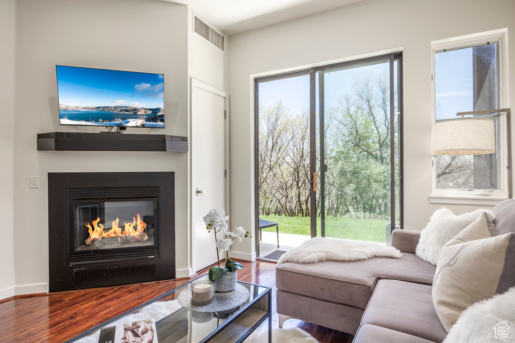 Living room with a glass covered fireplace, wood finished floors, and baseboards