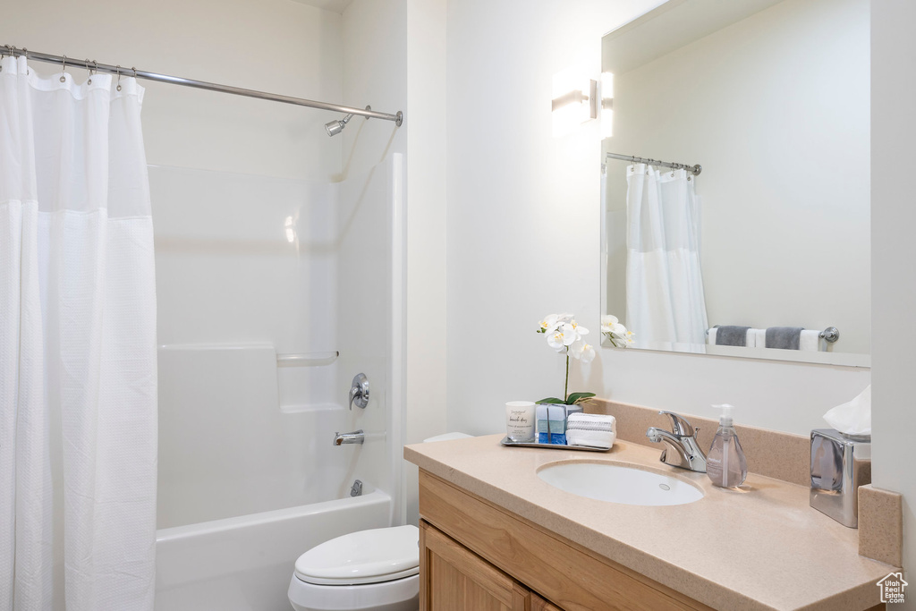 Full bathroom featuring toilet, vanity, and shower / bath combo with shower curtain