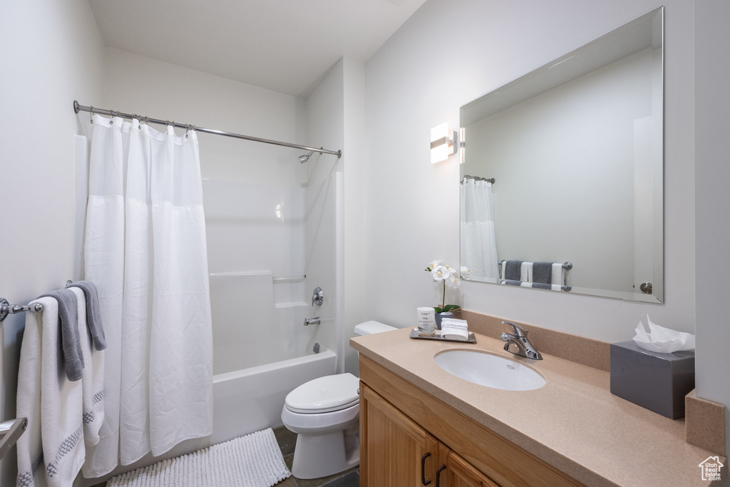 Full bathroom featuring toilet, vanity, and shower / bathtub combination with curtain