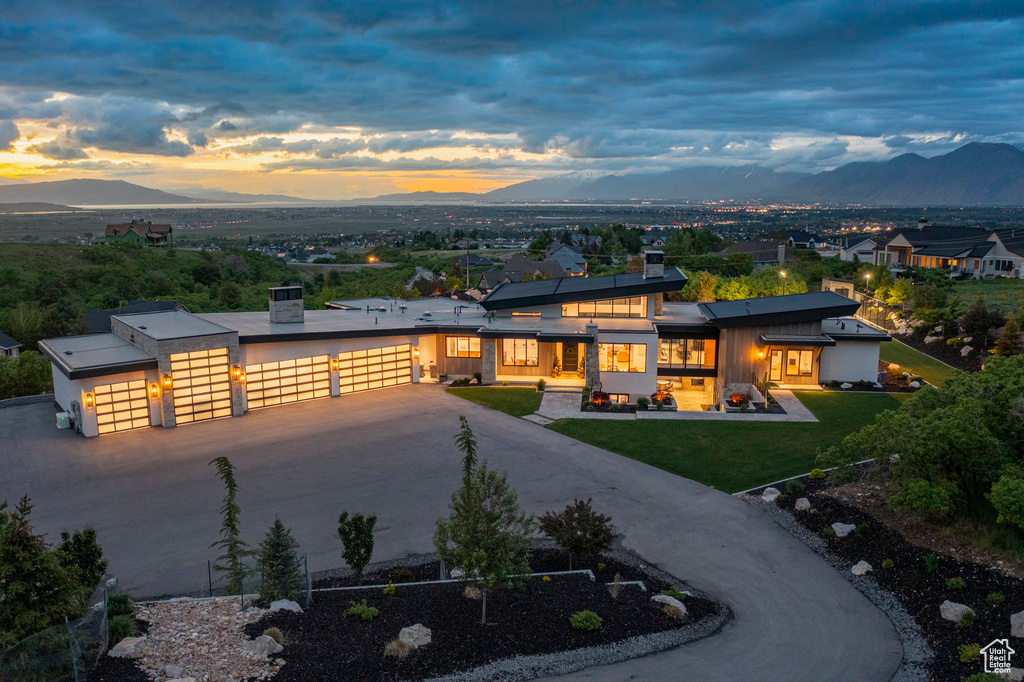Modern home featuring a mountain view, an attached garage, concrete driveway, and a front lawn