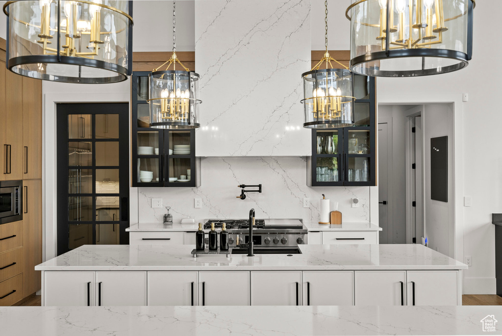 Bar area featuring a chandelier, a sink, tasteful backsplash, and hanging light fixtures