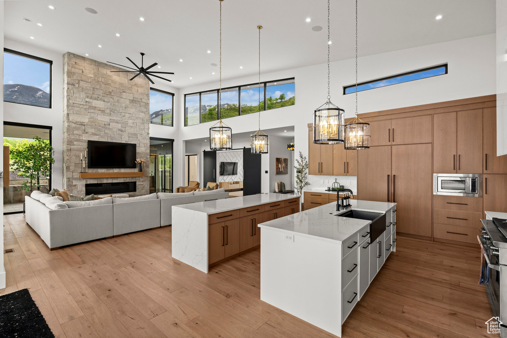 Kitchen with a spacious island, stainless steel appliances, a high ceiling, open floor plan, and light wood finished floors
