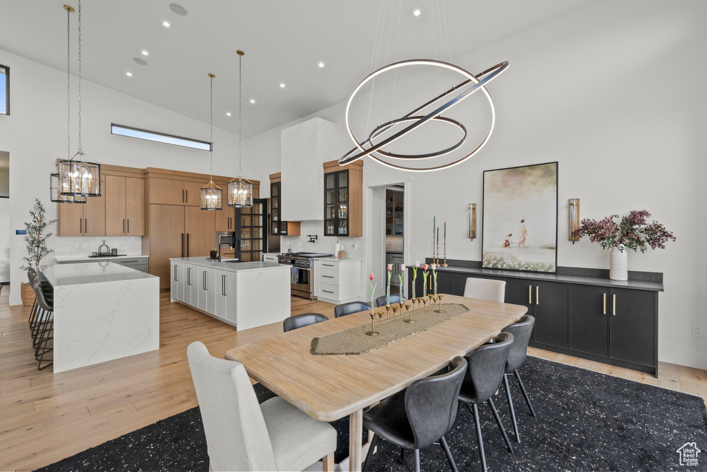 Dining area featuring high vaulted ceiling, a chandelier, and light wood-style flooring