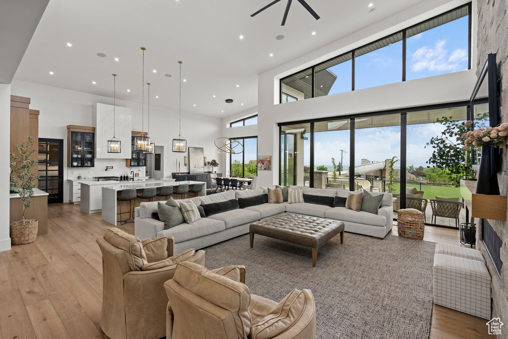 Living area with a towering ceiling, light wood-style floors, plenty of natural light, recessed lighting, and ceiling fan