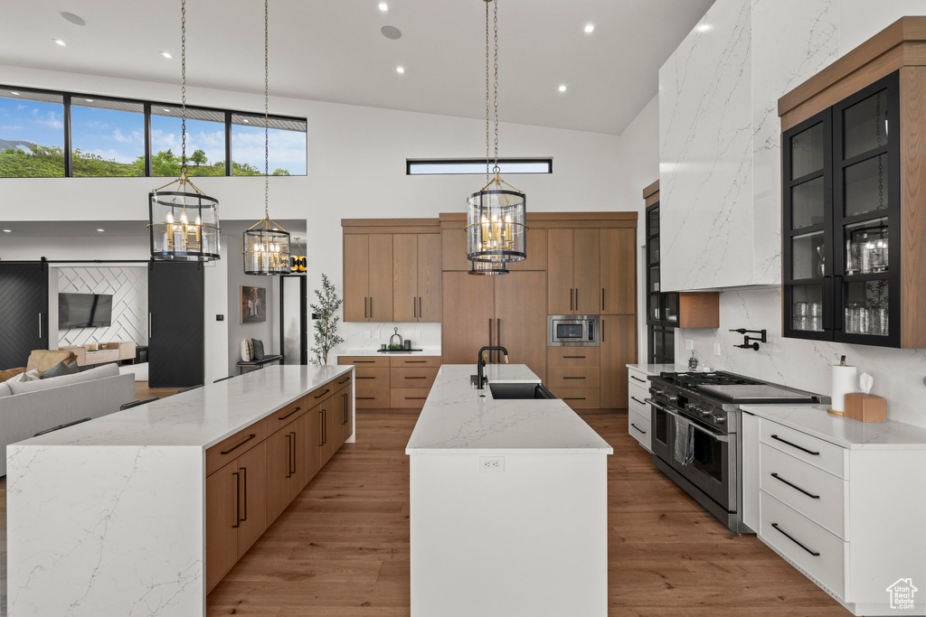 Kitchen with a chandelier, stainless steel appliances, a high ceiling, a large island, and a sink