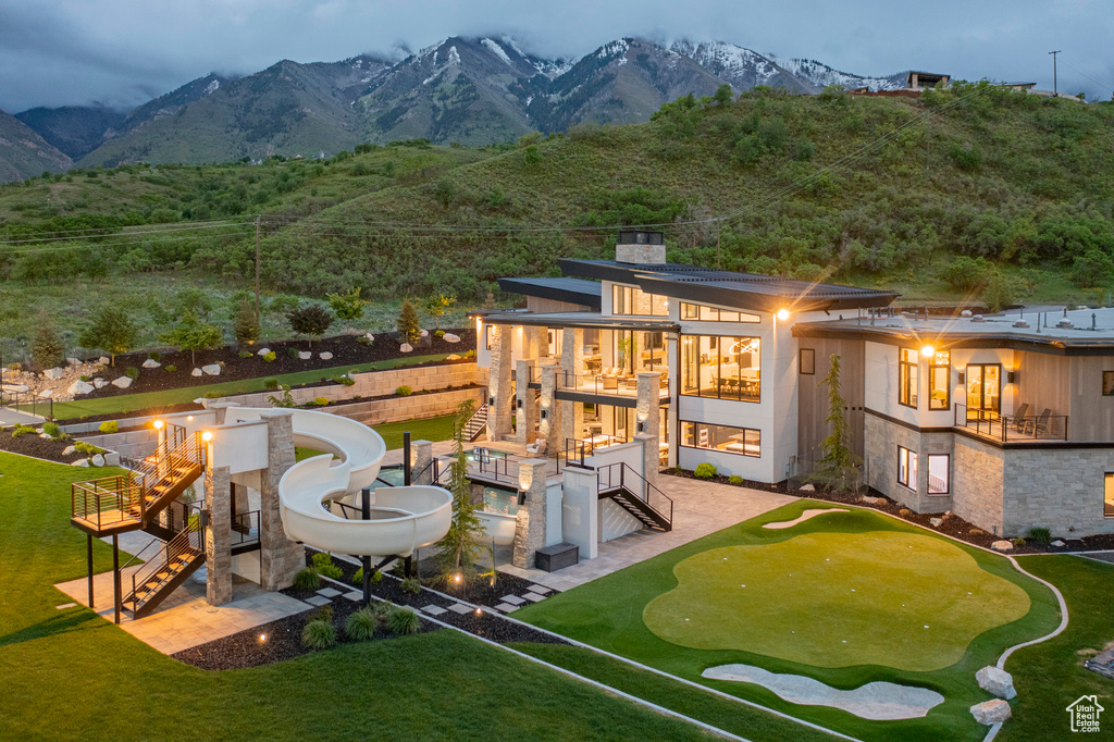 Rear view of property featuring stairs, a putting green, a balcony, a chimney, and a mountain view