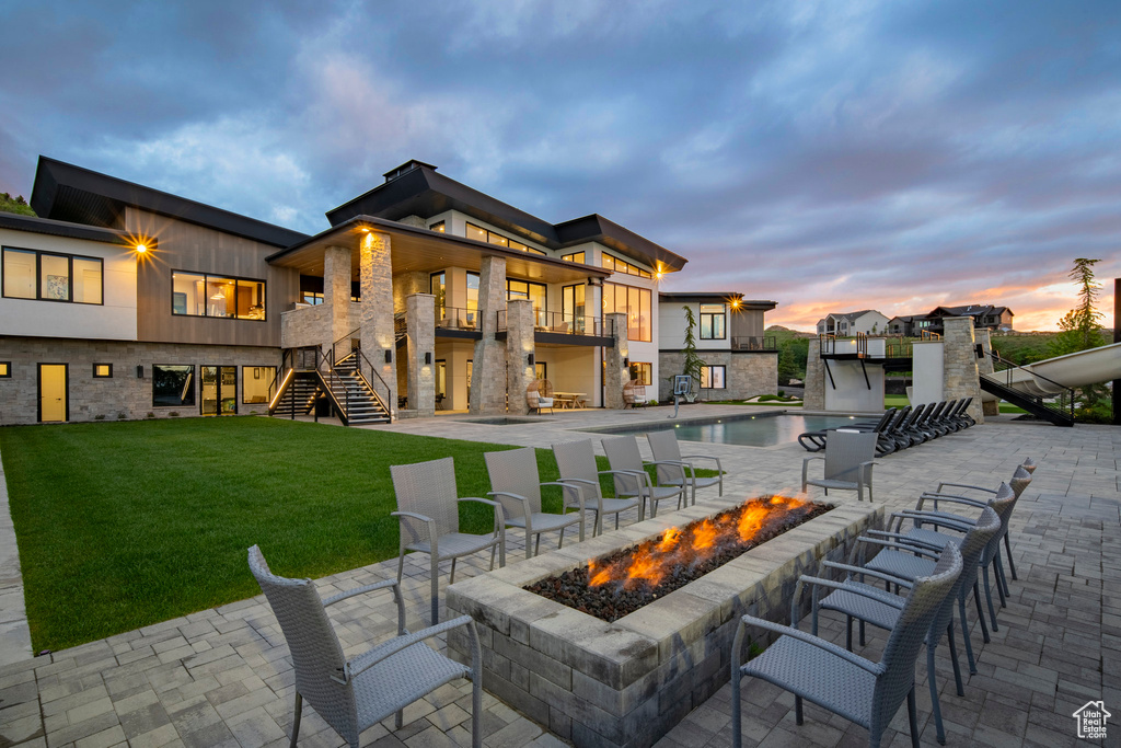 View of patio / terrace with an outdoor fire pit, stairs, a balcony, and an outdoor pool