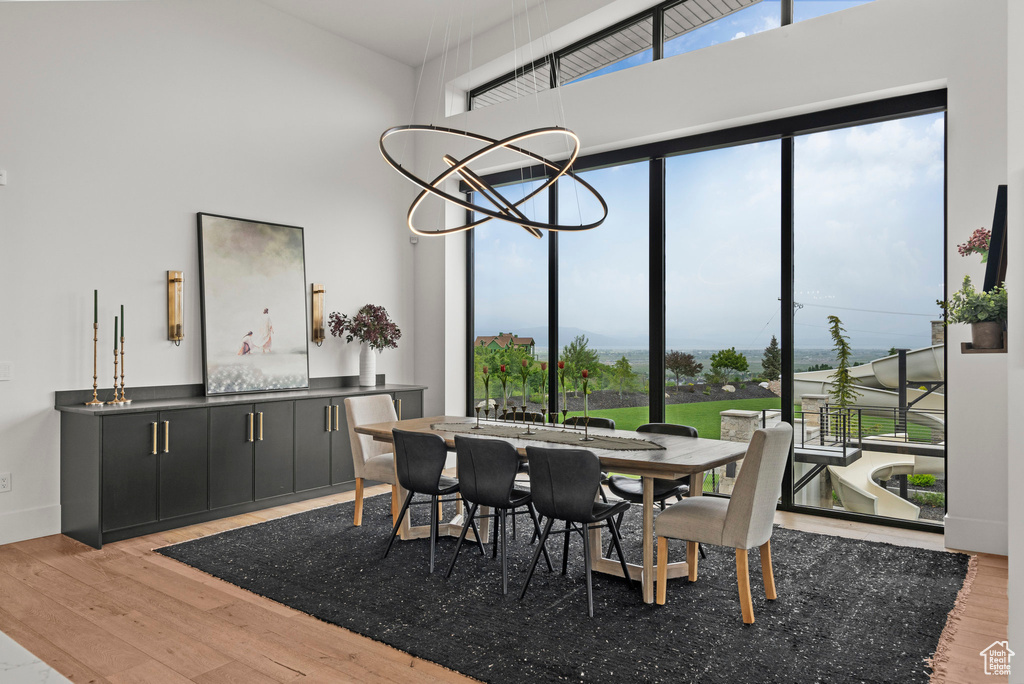 Dining space with wood finished floors, a chandelier, and a high ceiling