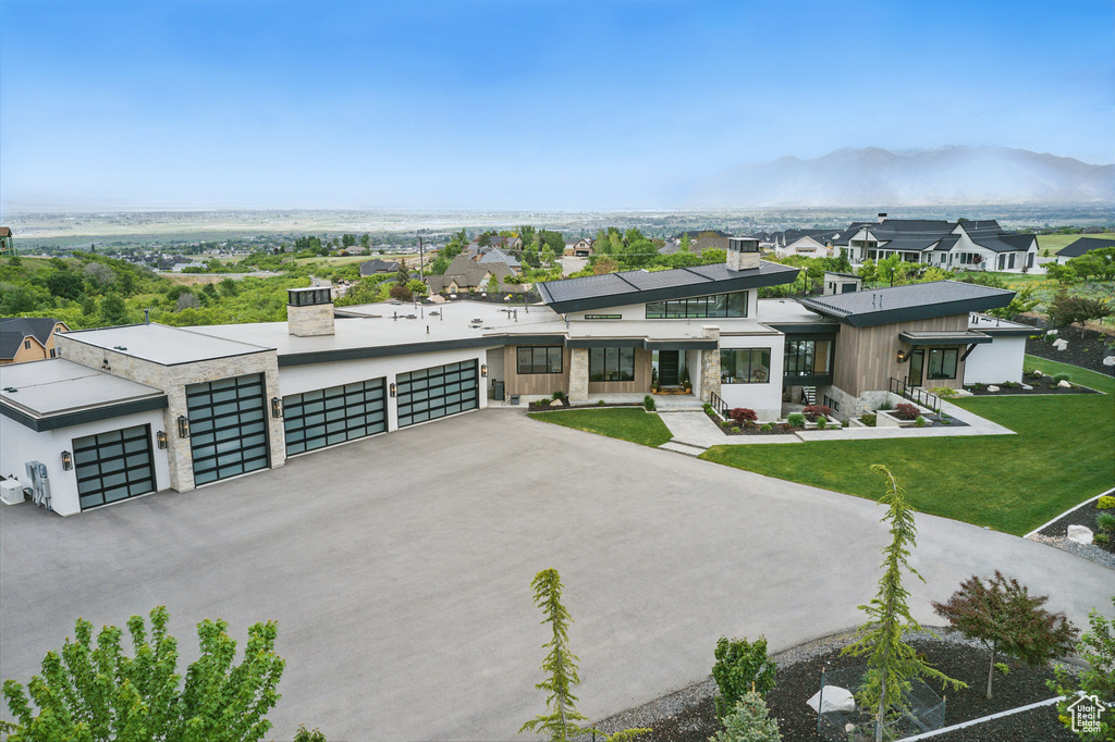 Contemporary home featuring a chimney, a front lawn, a mountain view, and asphalt driveway