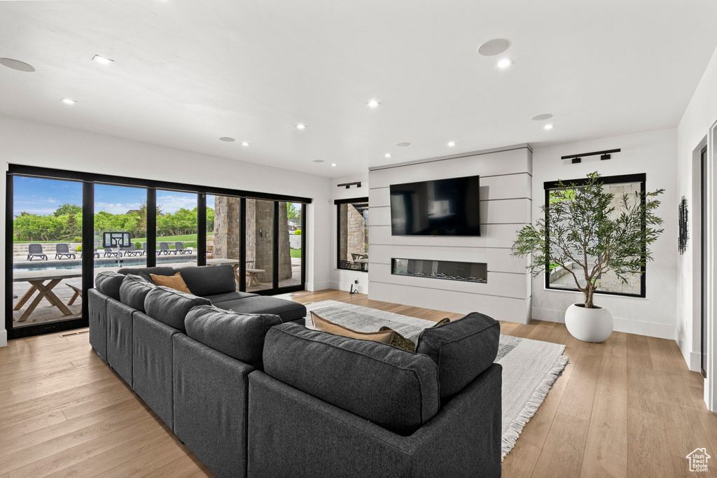 Living area featuring recessed lighting, a glass covered fireplace, baseboards, and light wood finished floors