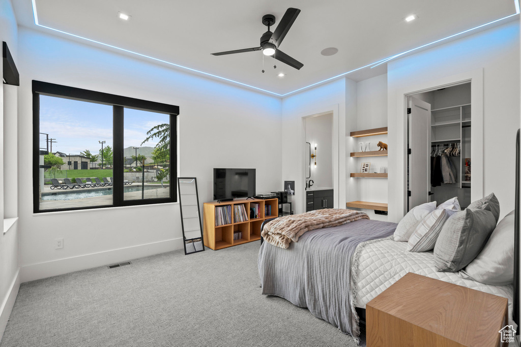 Bedroom with a spacious closet, carpet flooring, baseboards, ensuite bathroom, and a closet