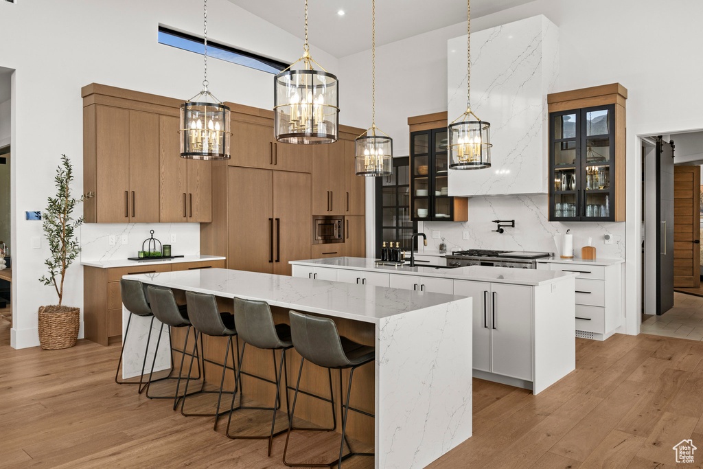 Kitchen with a large island, high vaulted ceiling, a chandelier, light wood-style floors, and stainless steel microwave