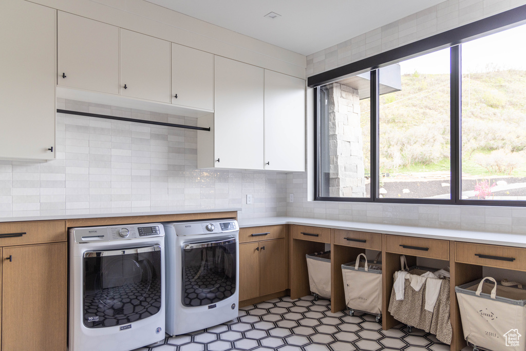 Washroom with cabinet space, separate washer and dryer, and healthy amount of natural light
