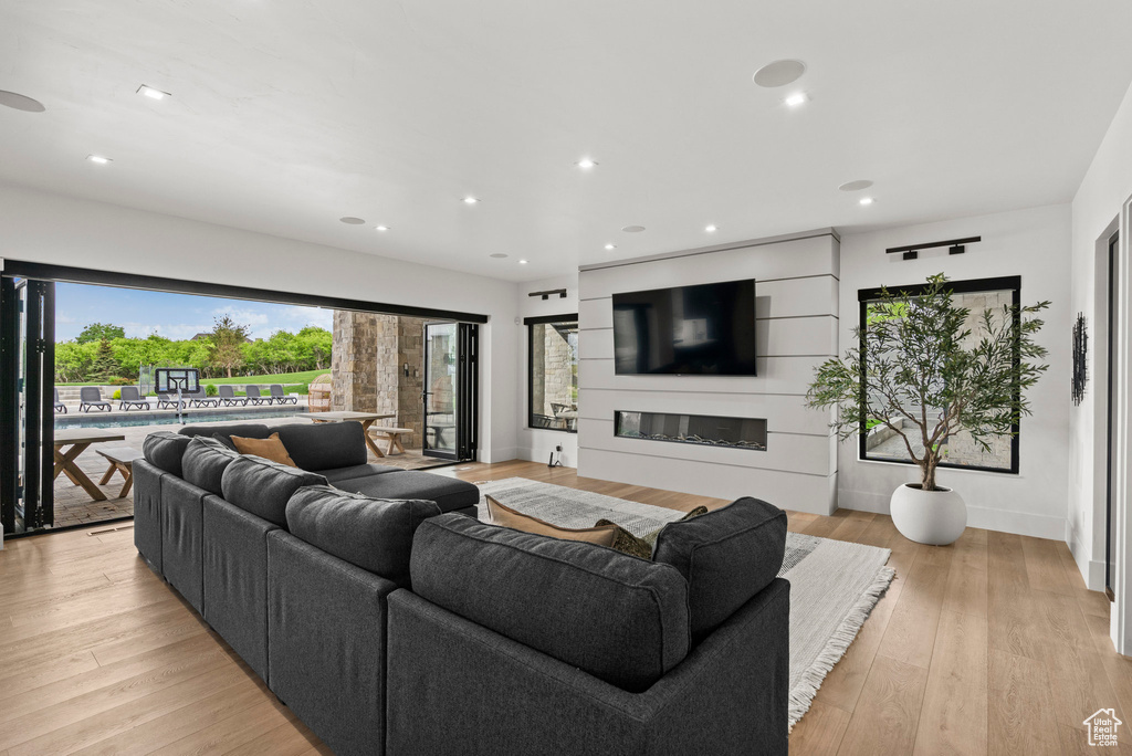 Living room featuring a glass covered fireplace, light wood finished floors, recessed lighting, and baseboards